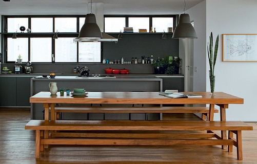 No projeto da SAO Arquitetura, a cozinha virou parte do living depois de aberta para a sala de jantar, com mesa e bancos de madeira