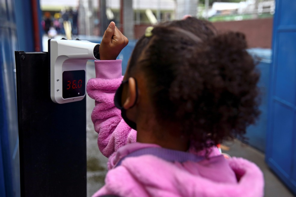 Menina mede temperatura no pulso na entrada da escola no dia de retomada das aulas com 100% de capacidade em São Paulo, no dia 18 de outubro. — Foto: Carla Carniel/Reuters