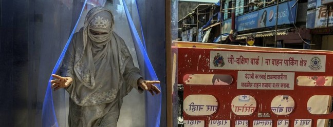 Mulher passa por um túnel de desinfecção em Mumbai, em abril de 2020. Cidade de 20 milhões de habitantes é agora responsável por 20% das infecções por coronavírus na Índia e quase 25% das mortes — Foto: ATUL LOKE / The New York Times
