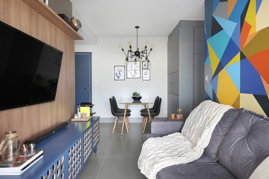 Na sala de estar do projeto da designer de interiores Elvira Monteiro, pintura geométrica na parede por Ricardo Kaur