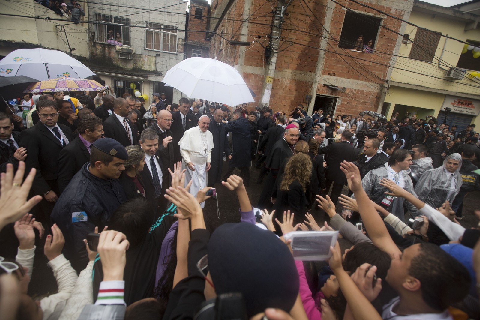 Pessoas saúdam o Papa Francisco, ao centro, enquanto ele visita a favela de Varginha, no Rio, em 25 de julho de 2013 — Foto: Victor R. Caivano / AP
