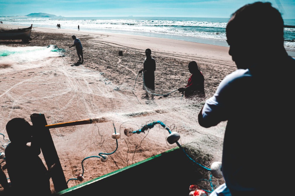Pescadores seguram rede de pesca na areia de praia de Florianópolis — Foto: Tiago Ghizoni/NSC