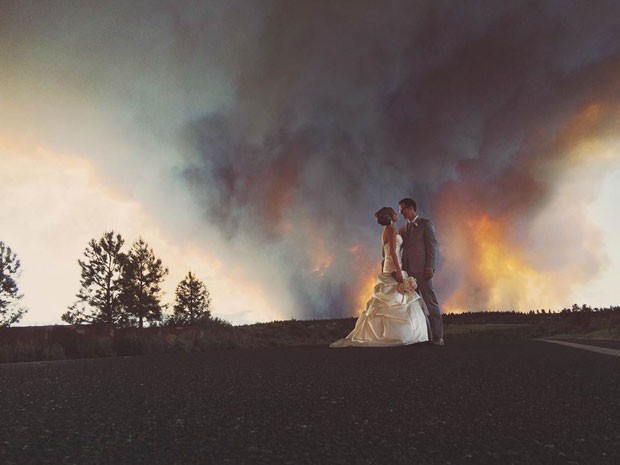 Michael Wolber e April Hartley foram evacuados do próprio casamento devido a um incêndio florestal, mas foram fotografados em uma cena incrível com as chamas ao fundo (Foto: Josh Newton/AP)