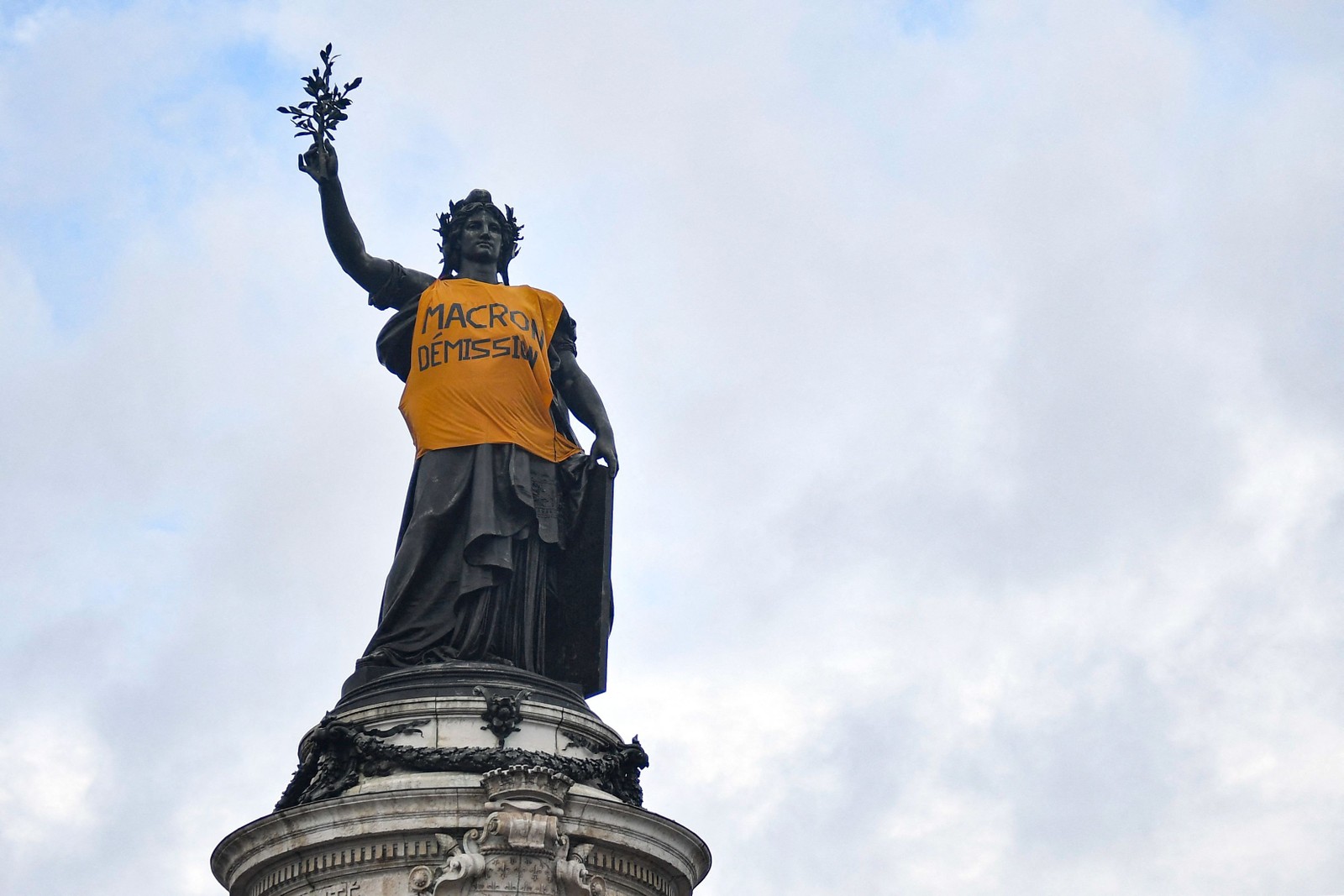 Um colete amarelo improvisado com o slogan "Macron, renuncie" adorna o Monumento à República, na Praça da República, em Paris — Foto: JULIEN DE ROSA / AFP