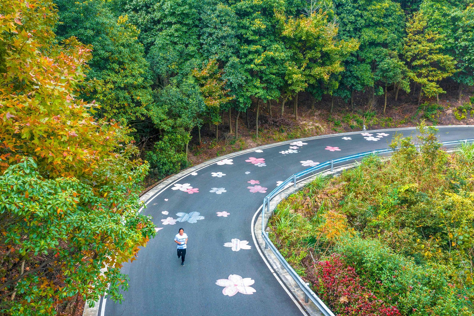 Mulher corre por uma estrada com imagens de flores em Ningbo, na província de Zhejiang, leste da China.  — Foto: AFP