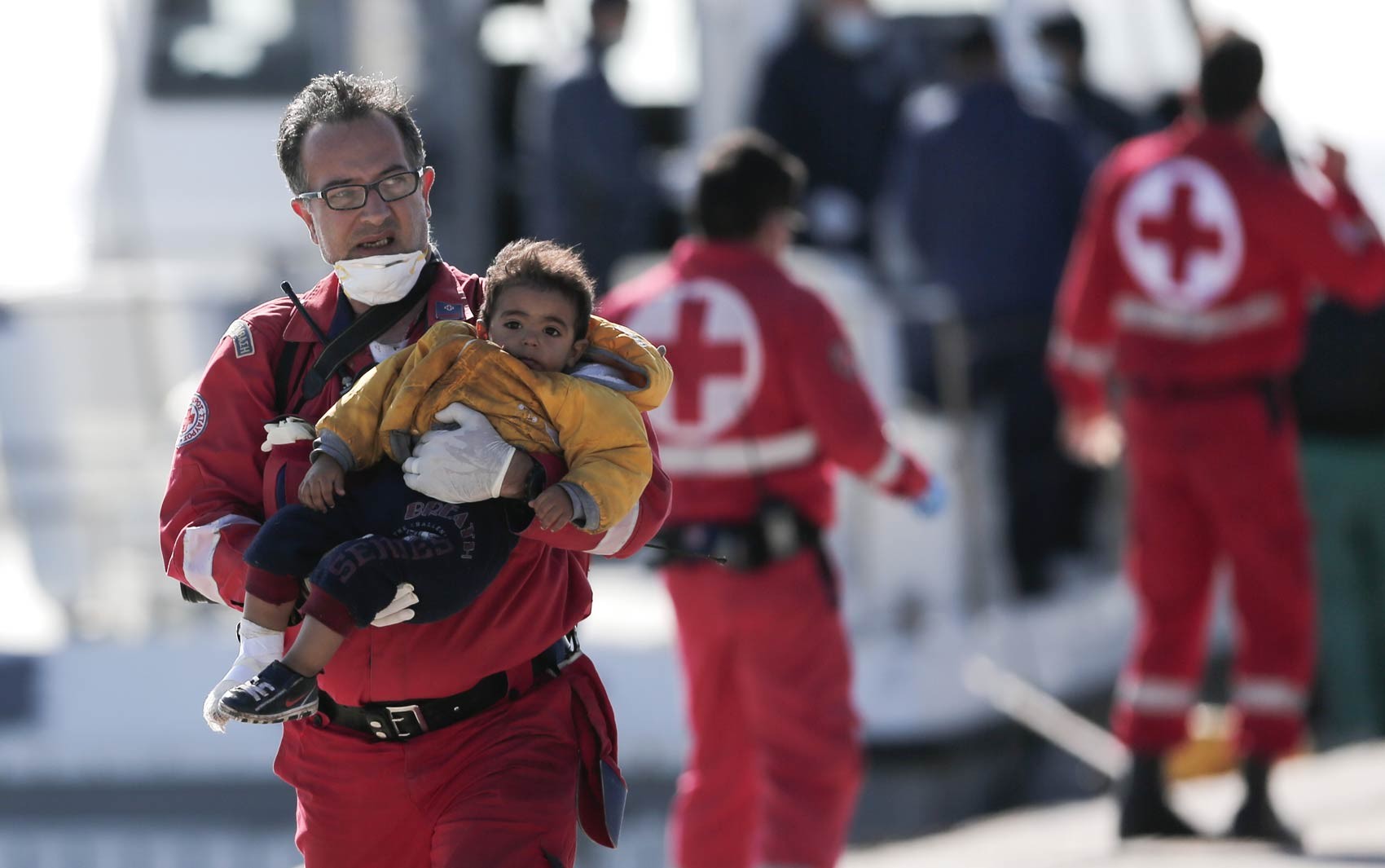 Voluntário da Cruz Vermelha carrega uma criança desembarcada de um navio de frete que levava cerca de 750 refugiados, a maioria síria, que tentavam chegar à Europa, em um porto de Creta, Grécia. O navio parou de funcionar a 70 milhas náuticas do porto (Foto: Petros Giannakouris/AP)