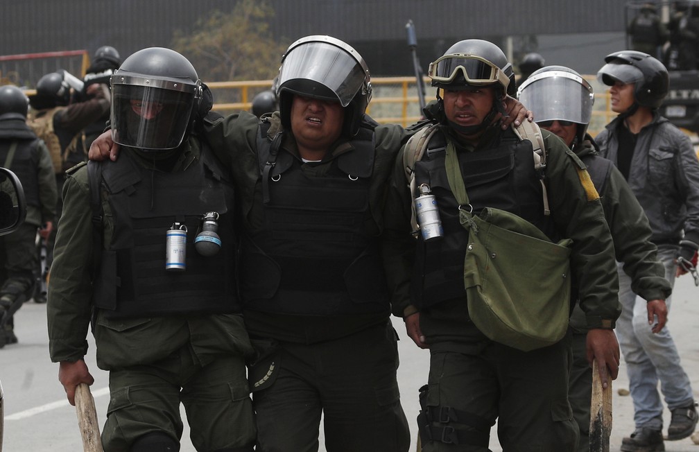 Policiais carregam colega ferido durante confronto em La Paz, na Bolívia, nesta segunda-feira (11) — Foto: Juan Karita/AP Photo