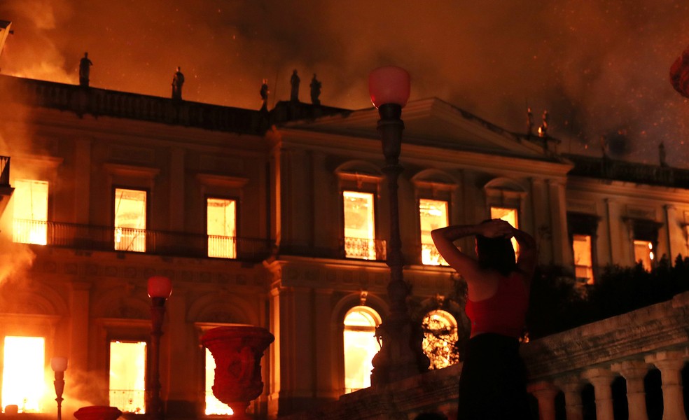 Uma mulher reage ao ver o incêndio no prédio do Museu Nacional, no Rio de Janeiro, na noite de domingo (2) (Foto: Ricardo Moraes/Reuters)