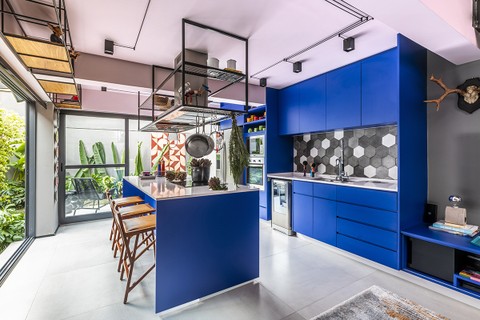 Os armários da cozinha são uma continuação do rack da sala, ambos em um tom forte de azul. Projeto arquiteto Luciano Dalla Marta