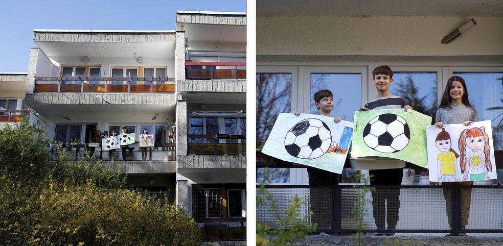 Os irmãos Ivan, Vince e Vilma Posta posam para foto com desenhos do que sentem falta durante o isolamento na varanda de sua casa em Budapeste, Hungria — Foto: Bernadett Szabo/Reuters