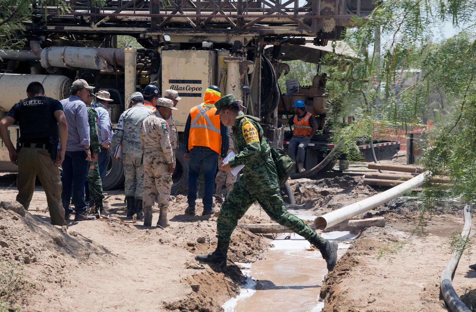 Trabalhadores e soldados circulam ao redor dos muitos canos que extraem jatos de água dos poços onde ficaram presos os mineiros — Foto: Julio Cesar AGUILAR / AFP