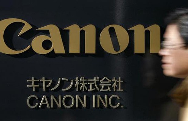 Homem passa pela fachada da sede da Canon Inc. em Tóquio (Foto: Reuters)