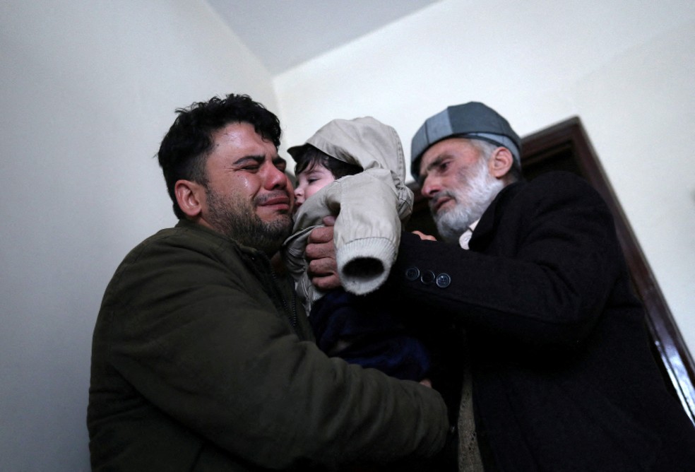 Hamid Safi chora ao entregar Sohail a seu avô Mohammad Qasem Razawi, em Cabul — Foto: Ali Khara/Reuters