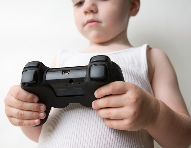 Boy holding video game control against white. (Foto: Getty Images/iStockphoto)