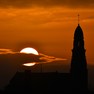 Foto: (Sol se põe atrás de uma igreja católica em Saint-Fiacre-sur-Maine, no oeste da França / Loic Venance/AFP)