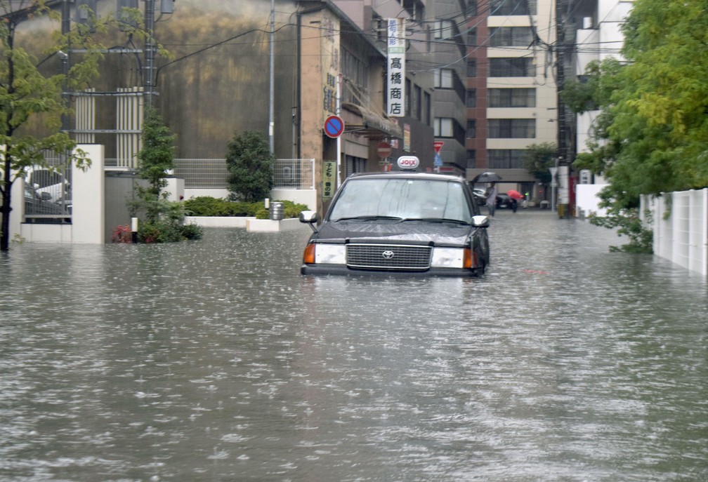 Um táxi fica preso em uma rua inundada na região de Saga, sul do Japão, nesta quarta-feira (28). — Foto: Kyodo News via AP