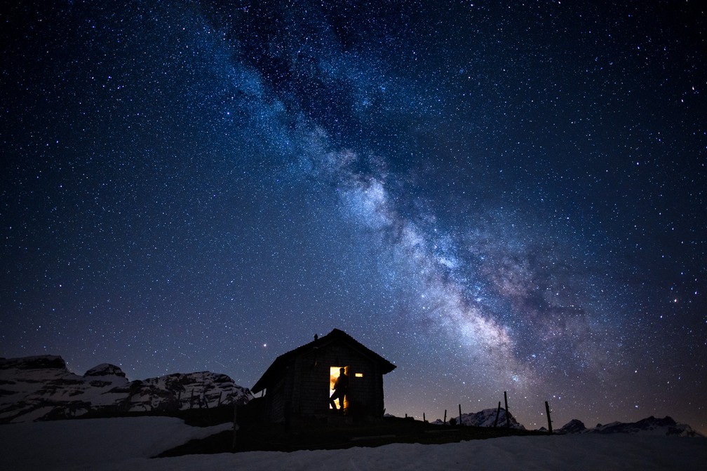 Um homem observa o céu estrelado com a via láctea em Ormont Valley, na Suíça — Foto: Anthony Anex/Keystone via AP