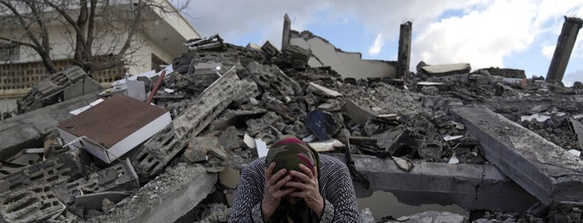 Mulher se senta em meio aos escombros em Nurdagi, arredores da cidade de Osmaniye, sul da Turquia, nesta terça (7) — Foto: Khalil Hamra/AP