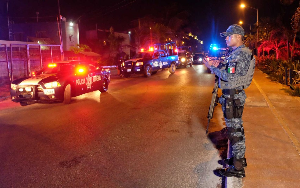 Policial federal está de guarda na área onde pelo menos cinco pessoas, incluindo um policial, foram mortos em tiroteio em Puerto Juarez, perto de Cancún (Foto: AFP Photo)