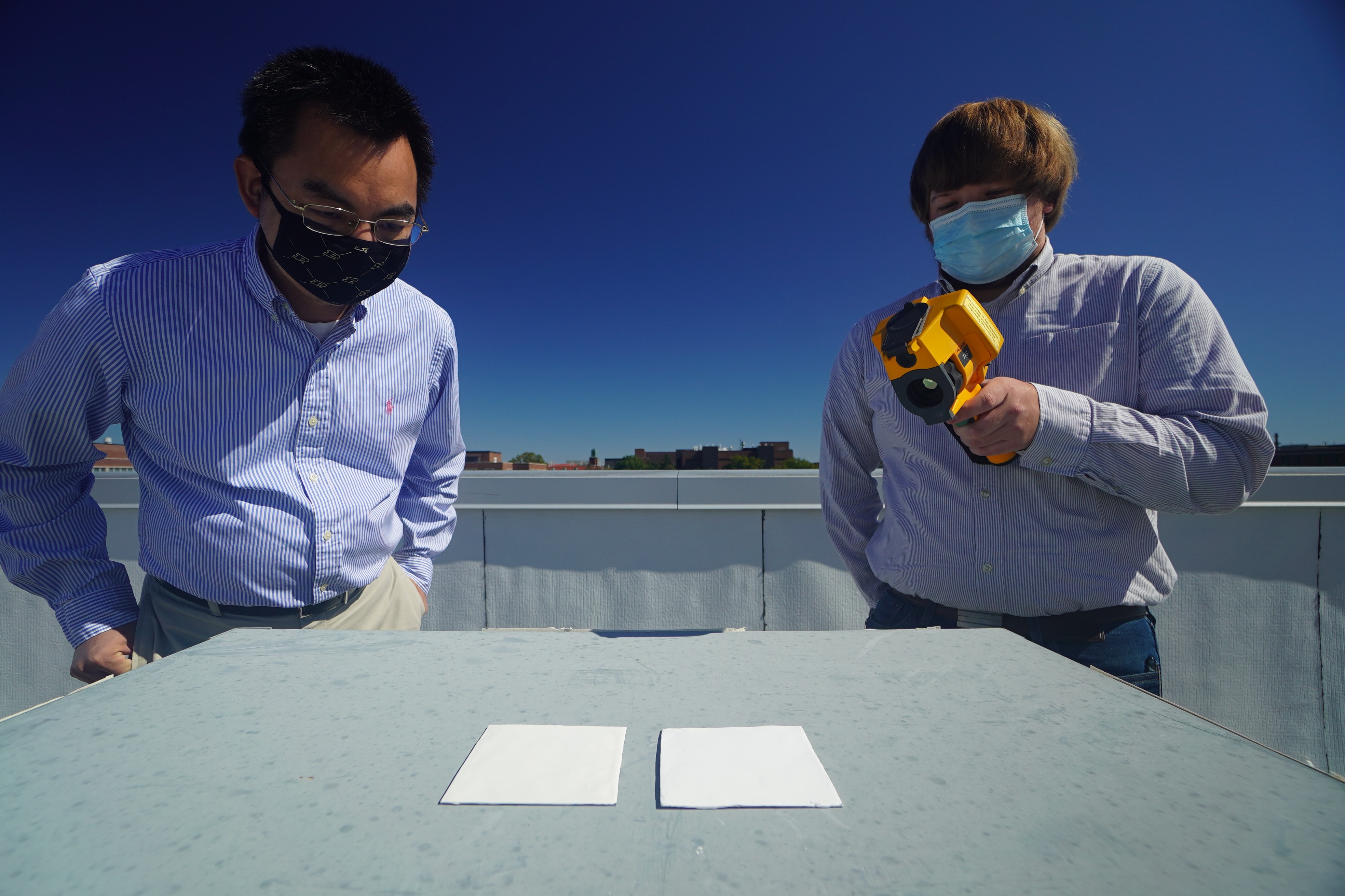 Os pesquisadores do Purdue, Xiulin Ruan e Joseph Peoples, usam uma câmera infravermelha para comparar o desempenho de resfriamento de amostras de tinta branca em um telhado (Foto:  Purdue University photo / Jared Pike)