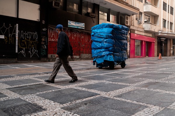 Homem caminha em rua com lojas e barracas fechadas no Centro de São Paulo.   — Foto: Marcelo Brandt/G1