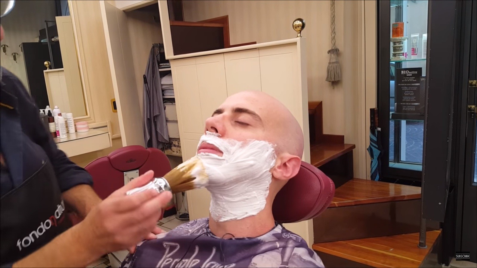 Uma cena habitual: Massimo sentado em uma cadeira sendo barbeado (Foto: Reprodução/Youtube)