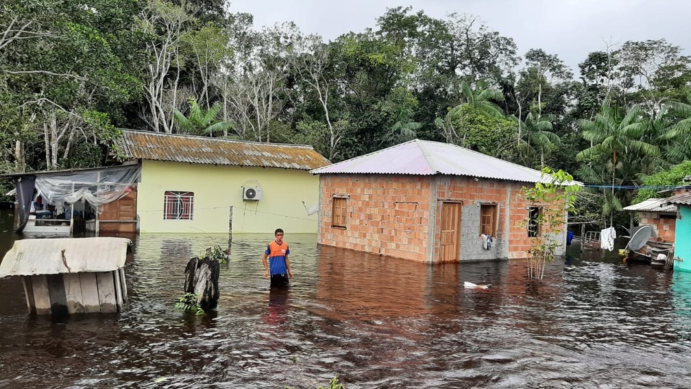 Jovem caminha em meio a rua inundada em Presidente Figueiredo (AM) — Foto: Francisco Carioca/Rede Amazônica