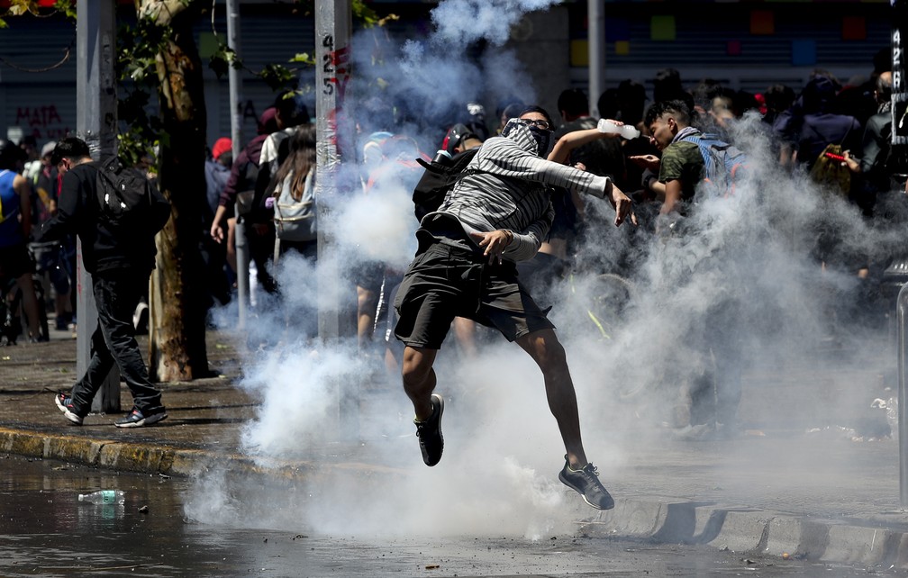 Manifestante rebate bomba de gás lacrimogêneo lançada por policiais durante protestos em Santiago, no Chile, nesta segunda-feira (21) — Foto: Miguel Arenas/AP Photo
