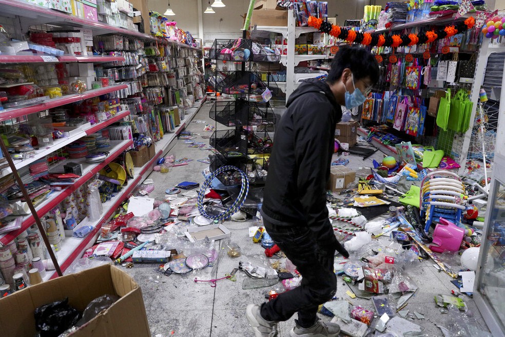 Trabalhador limpa supermercado após saques realizados durante os protestos em Santiago do Chile deste domingo (20) — Foto: Esteban Felix/AP