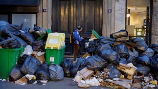 Homem passa por uma pilha de sacos de lixo que se acumulam desde que os coletores de lixo entraram em greve contra a proposta de reforma das pensões do governo francês — Foto: LUDOVIC MARIN/AFP
