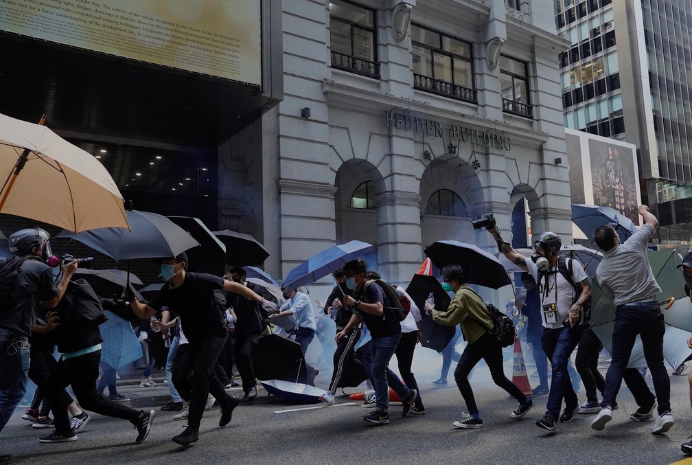 Manifestantes usam guarda-chuvas para se protegerem de gás lançado nesta segunda (11) durante protestos em Hong Kong. — Foto: Vincent Yu/AP