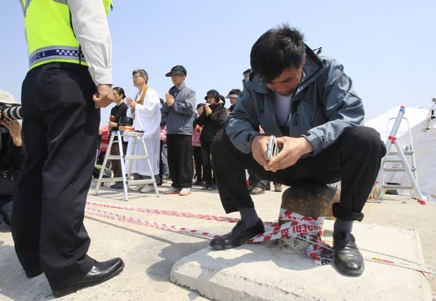 Parente de vítima do naufrágio chora no porto de Jindo enquanto aguarda operações de resgate (Foto: Ahn Young-joon/AP)