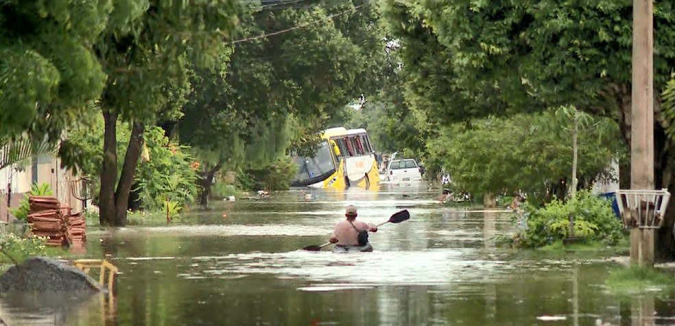 Homem anda de caiaque em rua alagada em Guriri — Foto: Reprodução/TV Gazeta