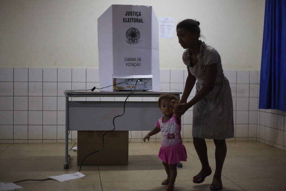 Eleitora do Tocantins deixa a cabine de votação com uma criança