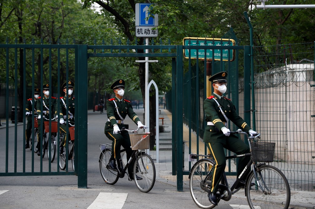 29 de abril - Policiais paramilitares chineses usam máscaras protetoras enquanto andam de bicicleta em Pequim, na China — Foto: Thomas Peter/Reuters