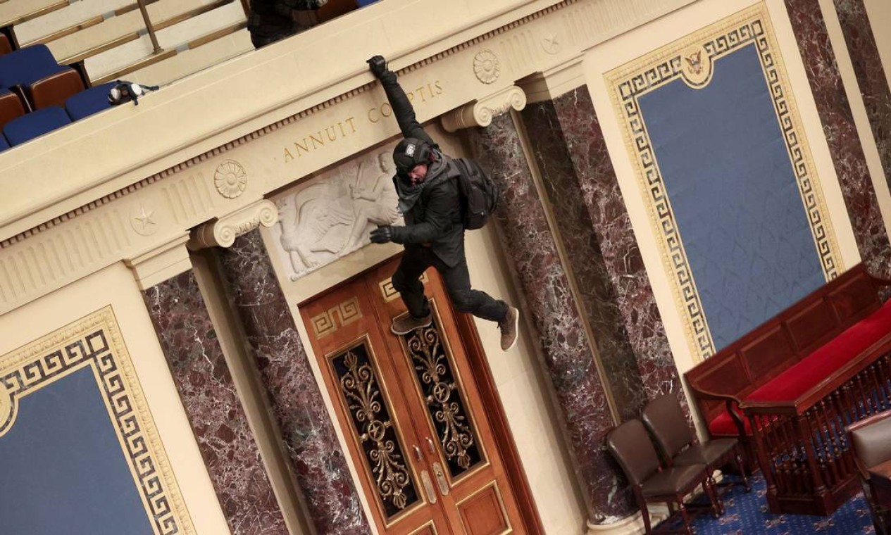 Um manifestante é visto pendurado na varanda do plenário do Senado  — Foto: WIN MCNAMEE / AFP