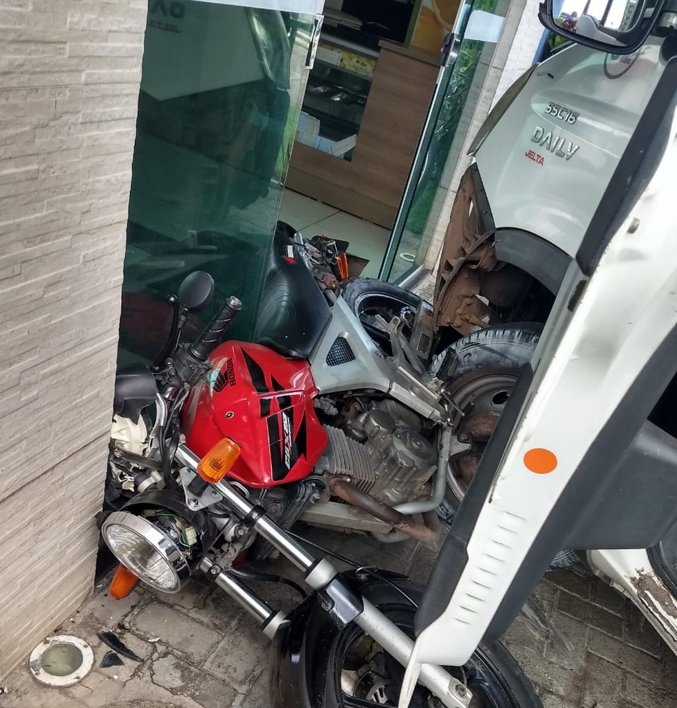 Roda de caminhão ficou presando no pneu da moto e na porta de vidro da lotérica — Foto: Francisco Filho