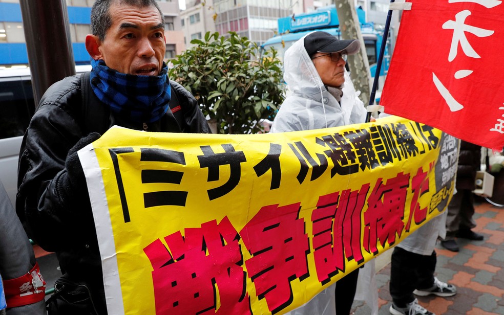 Manifestantes protestam contra simulação de remoção antimíssil no parque de diversões Tokyo Dome City, em Tóquio, no Japão, na segunda-feira (22), com faixa que diz ‘Simulação de remoção antimíssil é um exercício de guerra’ (Foto: Reuters/Kim Kyung-Hoon)