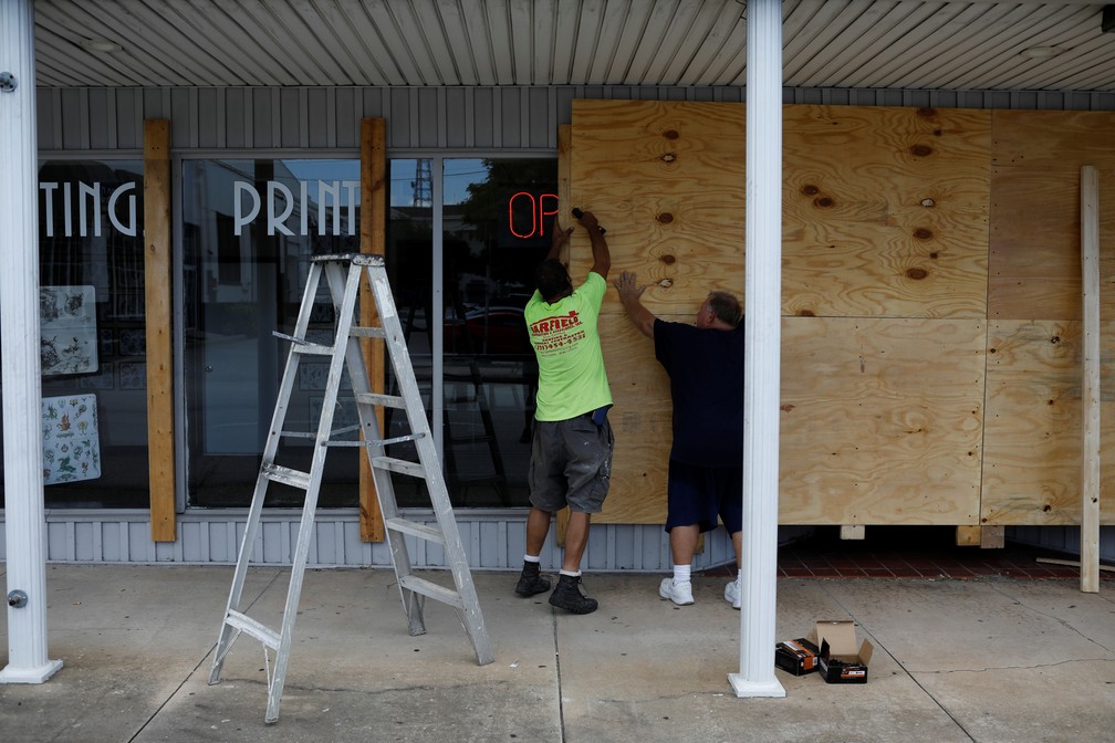 Homens colocam painéis em uma loja, na Flórida, após alerta sobre possível chegada do furacão Dorian — Foto: Marco Bello/Reuters