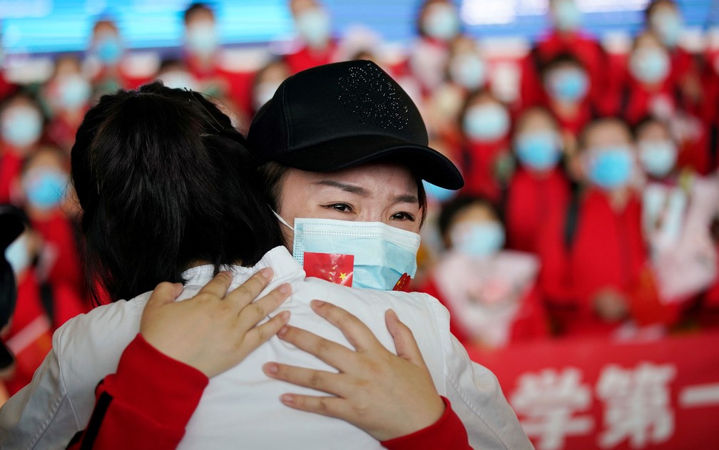 Membros de equipe médica se abraçam no Aeroporto Internacional Tianhe, em Wuhan, após o fim das restrições de viagem na província de Hubei, na China, na quarta-feira (8) — Foto: Reuters/Aly Song 