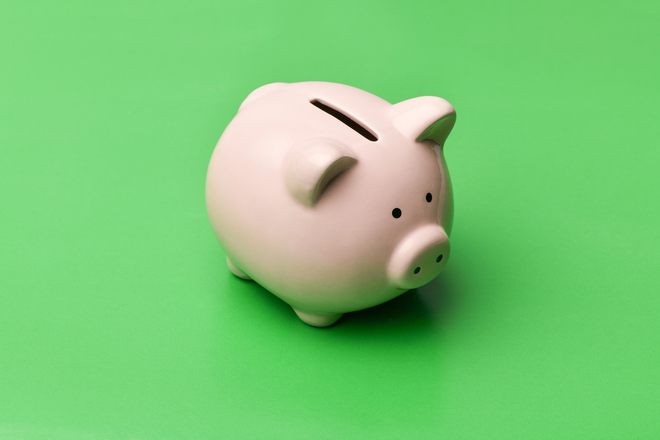 Pink piggy Bank in the shape of a pig stands in the center on a green background. Horizontal photography (Foto: Getty Images/iStockphoto)