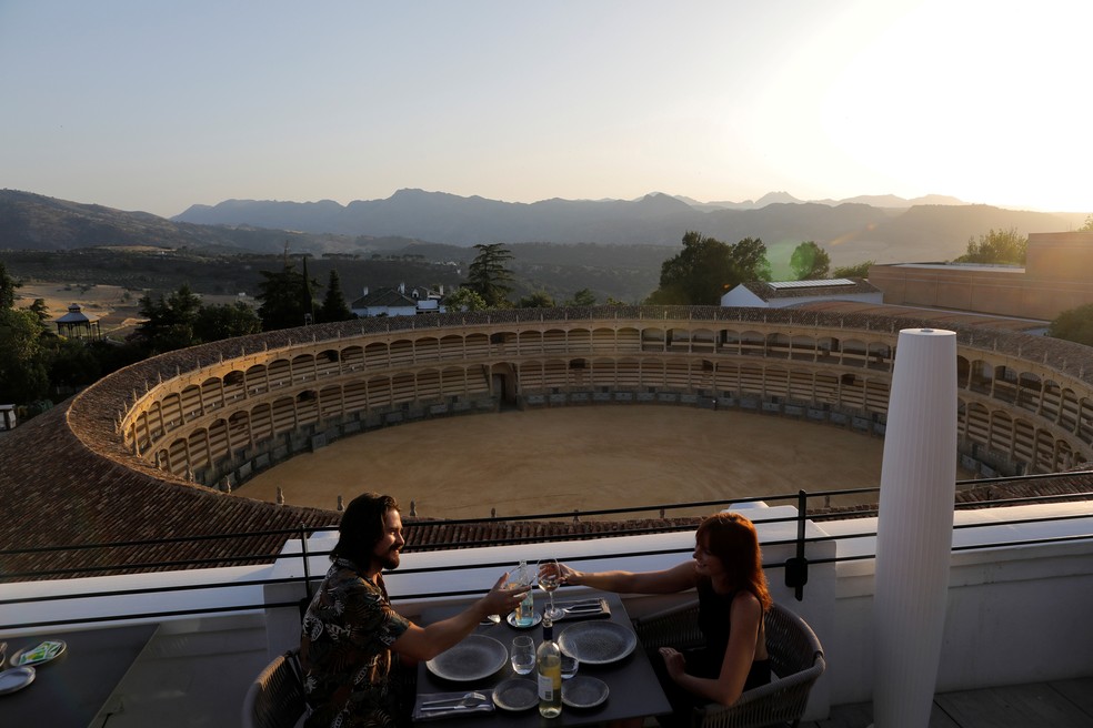 29 de junho - Casal de turistas australianos brinda com taças de vinho após relaxamento das restrições impostas para controlar a propagação de coronavírus (COVID-19), no restaurante do terraço do hotel Catalonia Ronda, em Ronda, sul da Espanha — Foto: Jon Nazca/Reuters