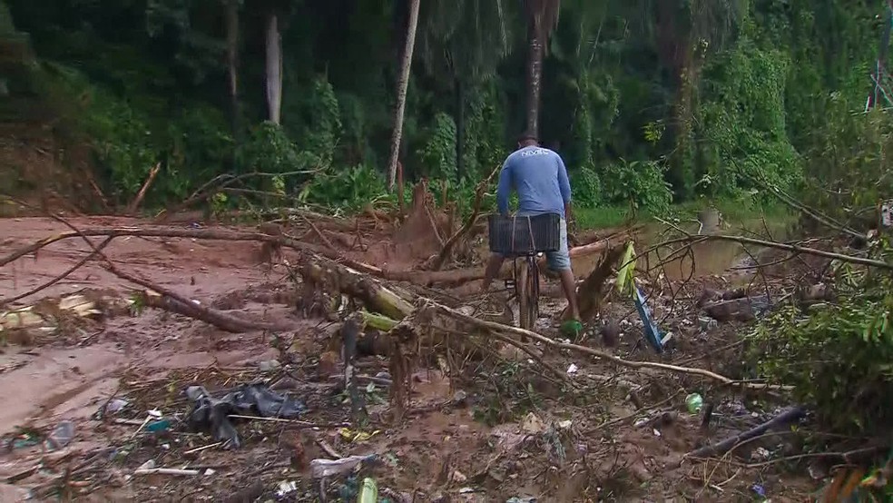 Na Estrada do Passarinho, homem tenta passar com bicicleta por via atingida pelo deslizamento — Foto: Reprodução/TV Globo