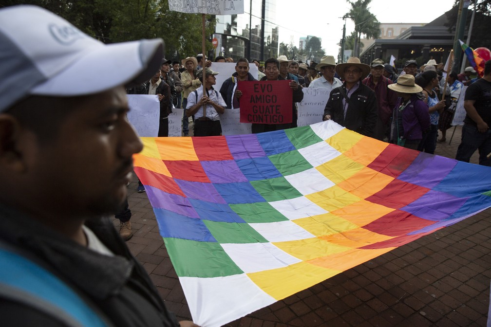 Em protesto na Guatemala nesta quinta-feira (14), apoiadores do ex-presidente da Bolívia Evo Morales estendem a bandeira indígena wiphala — Foto: Moises Castillo/AP Photo