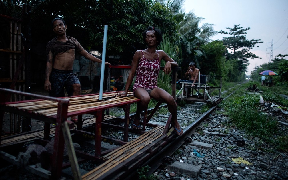 O casal de empurradores de carrinho Tyson Aguha e Joan Acebo esperam por passageiros em linha de trem de Manila, em foto de dia 19 de outubro — Foto: Noel Celis/AFP