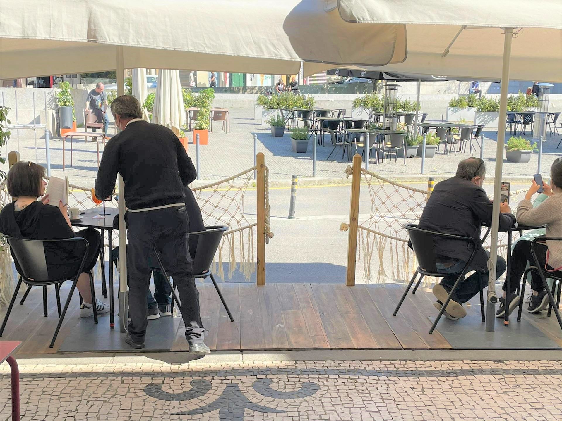 Garçom serve os primeiros clientes das mesas externas da Casa Guedes, no Porto, em Portugal