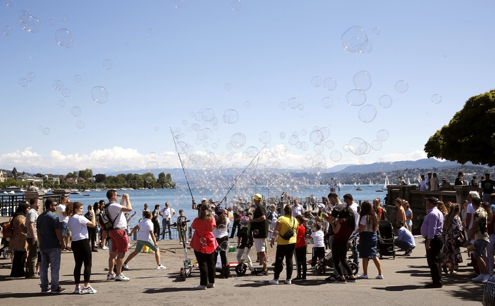 Pessoas assistem a homem que brinca com bolhas de sabão em Zurique, na Suíça, em 1 de junho — Foto: Arnd Wiegmann/Reuters