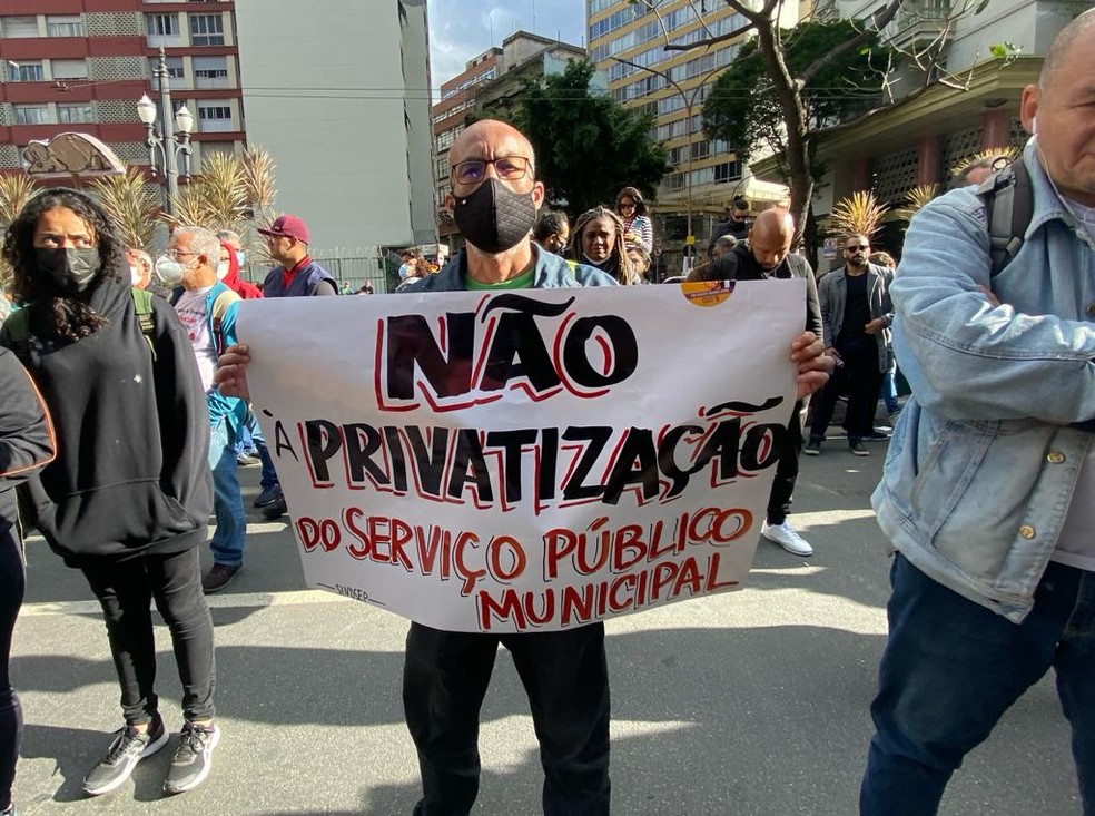 Servidor segurança cartaz contra o projeto do lei da Prefeitura que quer passar a administração de escolas municiais para OSs. — Foto: Celso Tavares