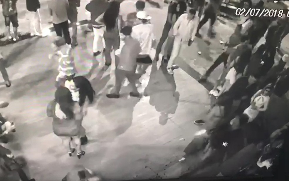 À direita, homem com roupa escura dispara; rajada pode ser vista na imagem (Foto: Imagem do circuito de segurança)