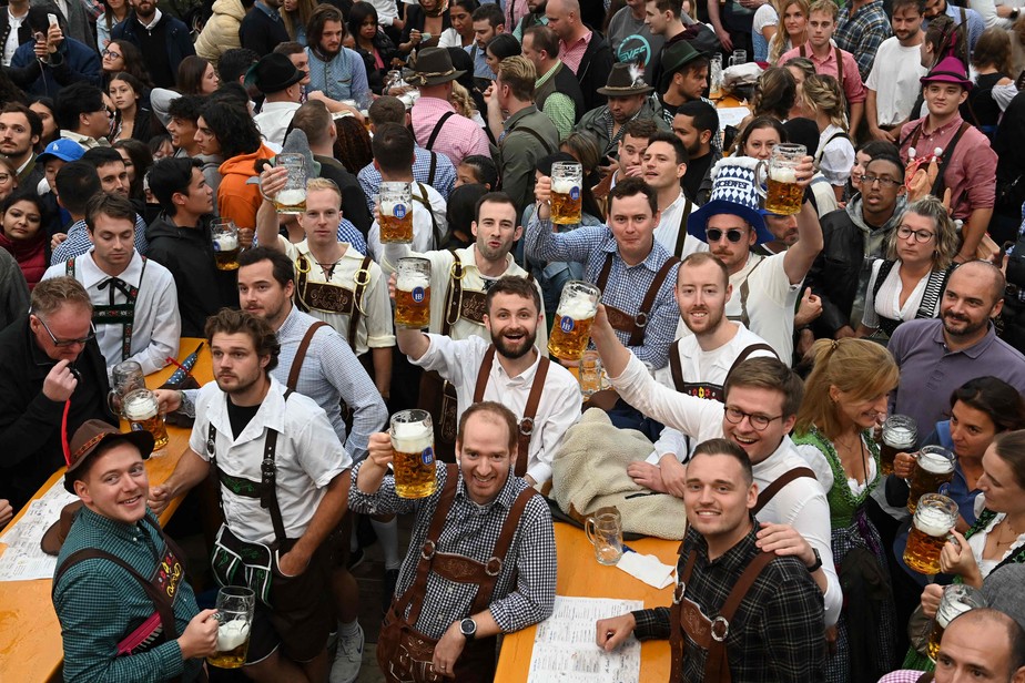 Visitantes seguram suas canecas de cerveja na abertura da Oktoberfest em Munique